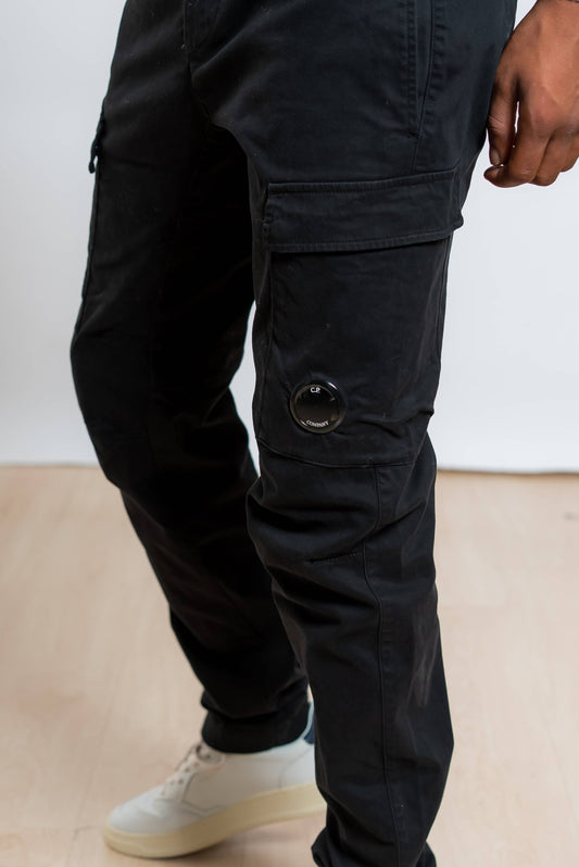 dettaglio della cp company lens sui pantaloni cargo satin stretch in cotone nero