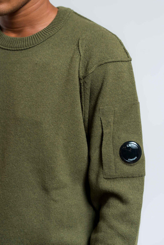 dettaglio della cp company lens sulla manica del maglione lambswool in lana verde