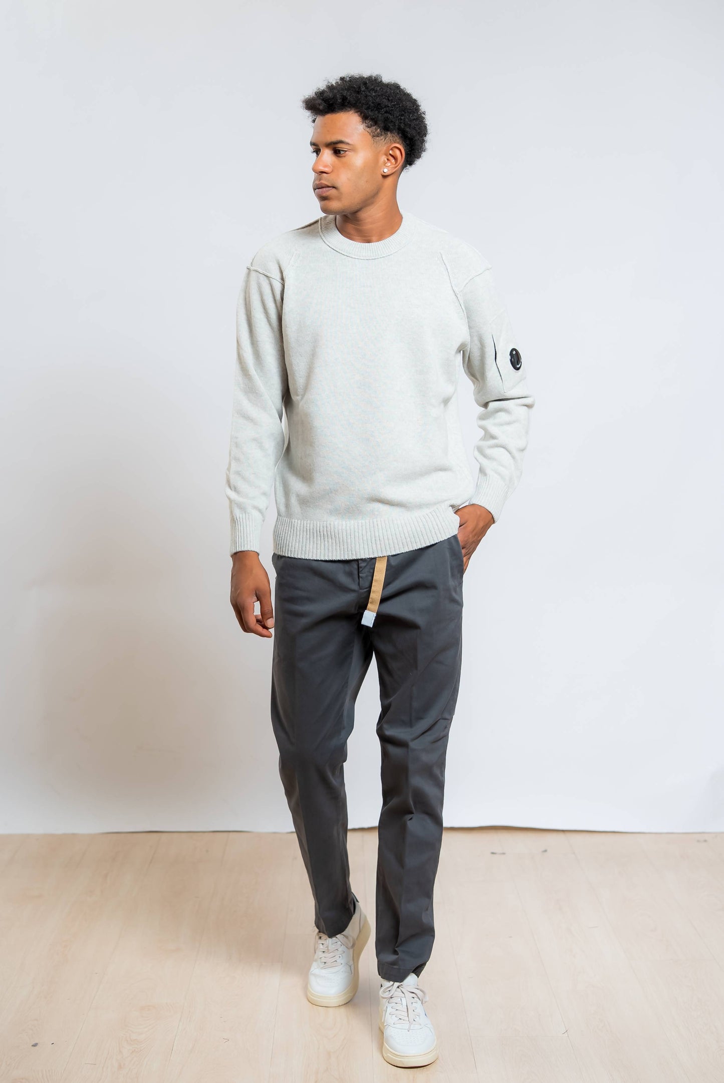 cp company maglione lambswool in lana grigia abbinato ad un pantalone grigio e sneakers bianche