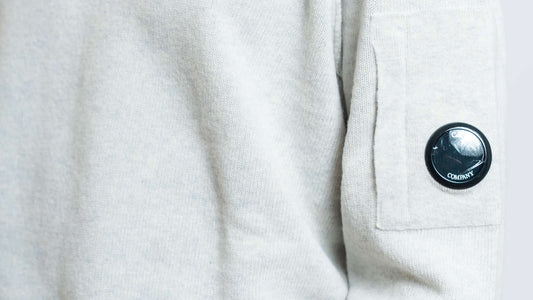 dettaglio del taschino con cp company lens e cuciture in rilievo del maglione lambswool in lana grigia