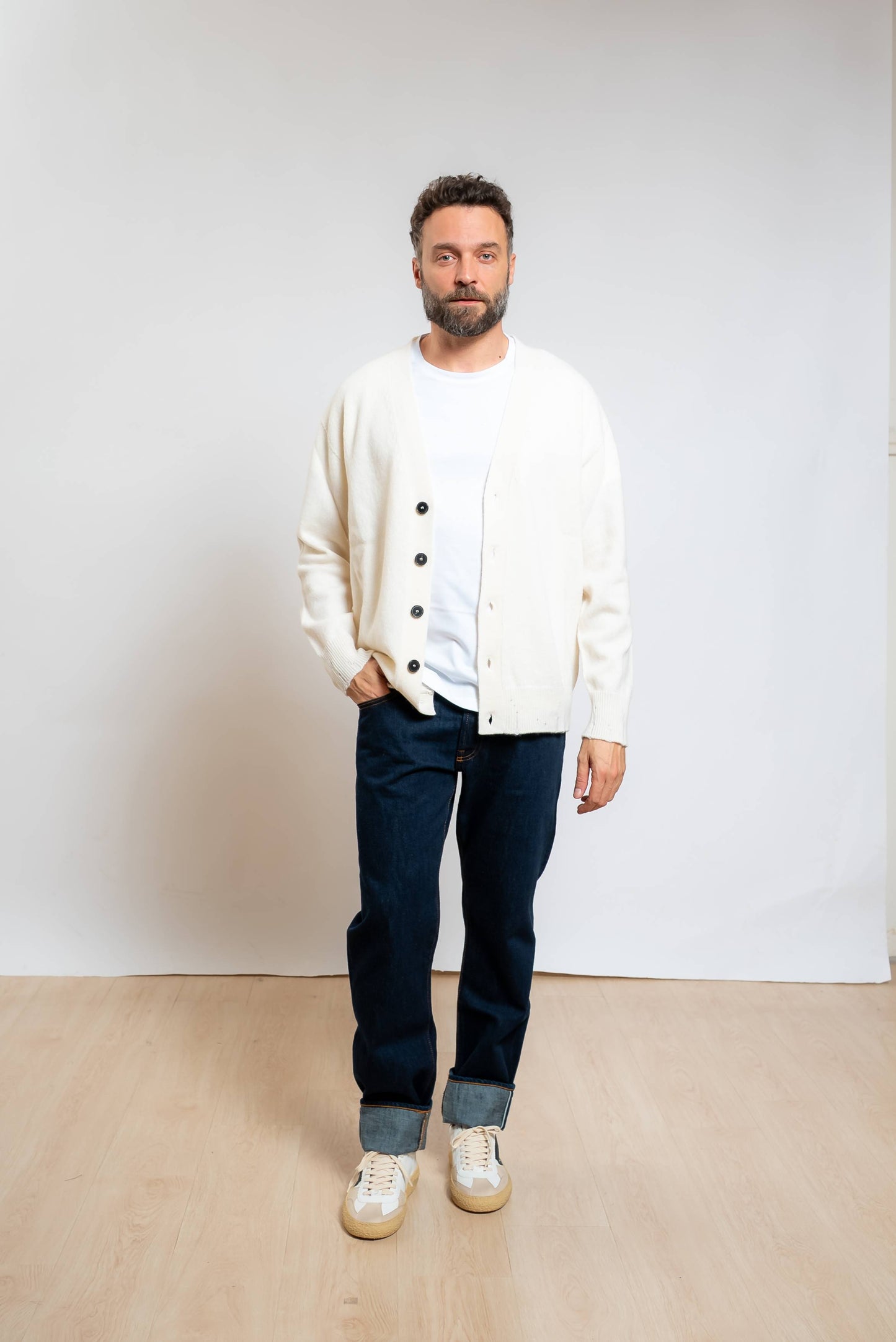 amaranto cardigan in lana e cashmere panna con scollo a v e rotture sugli orli abbinato ad una t-shirt bianca, jeans blu e sneakers bianche