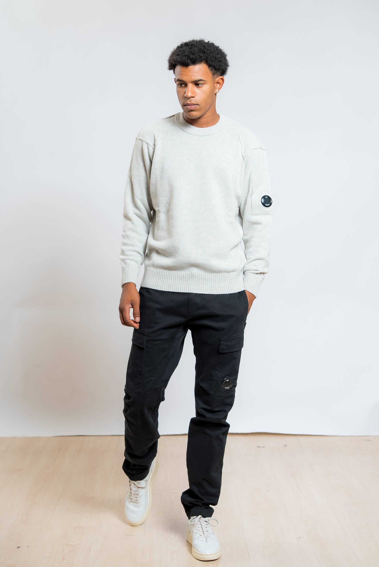 cp company pantaloni cargo satin stretch in cotone nero abbinati ad un maglione lambswool grigio