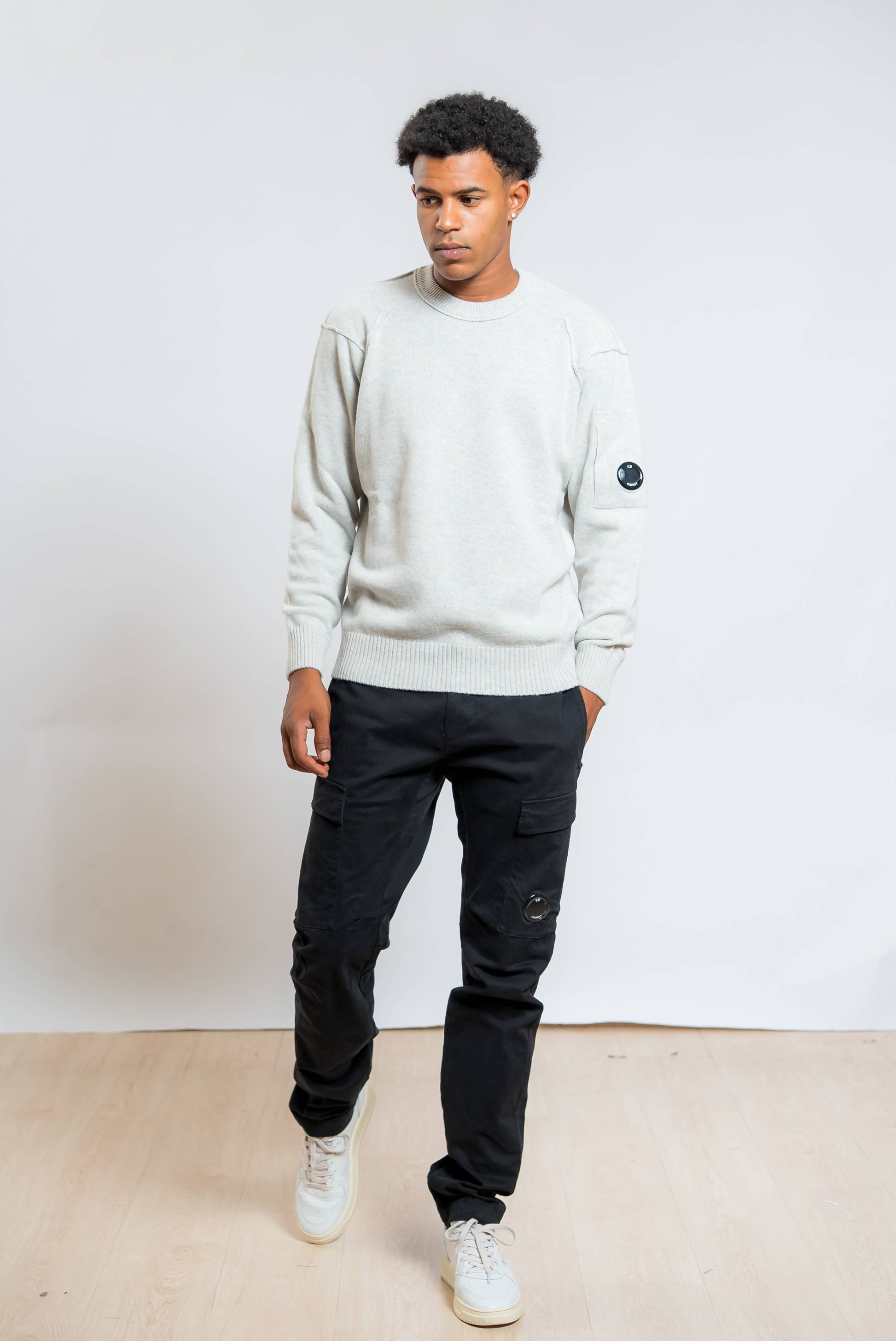 cp company pantaloni cargo satin stretch in cotone nero abbinati ad un maglione lambswool grigio