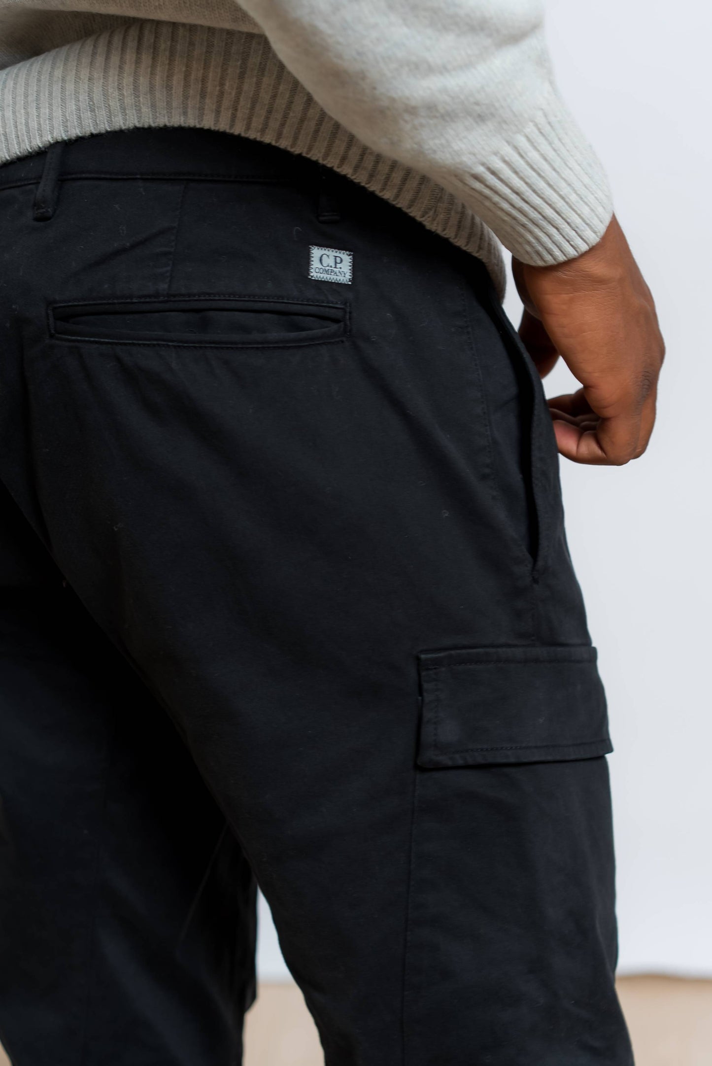 dettaglio tasca ed etichetta con logo cp company sui pantaloni cargo satin stretch neri 