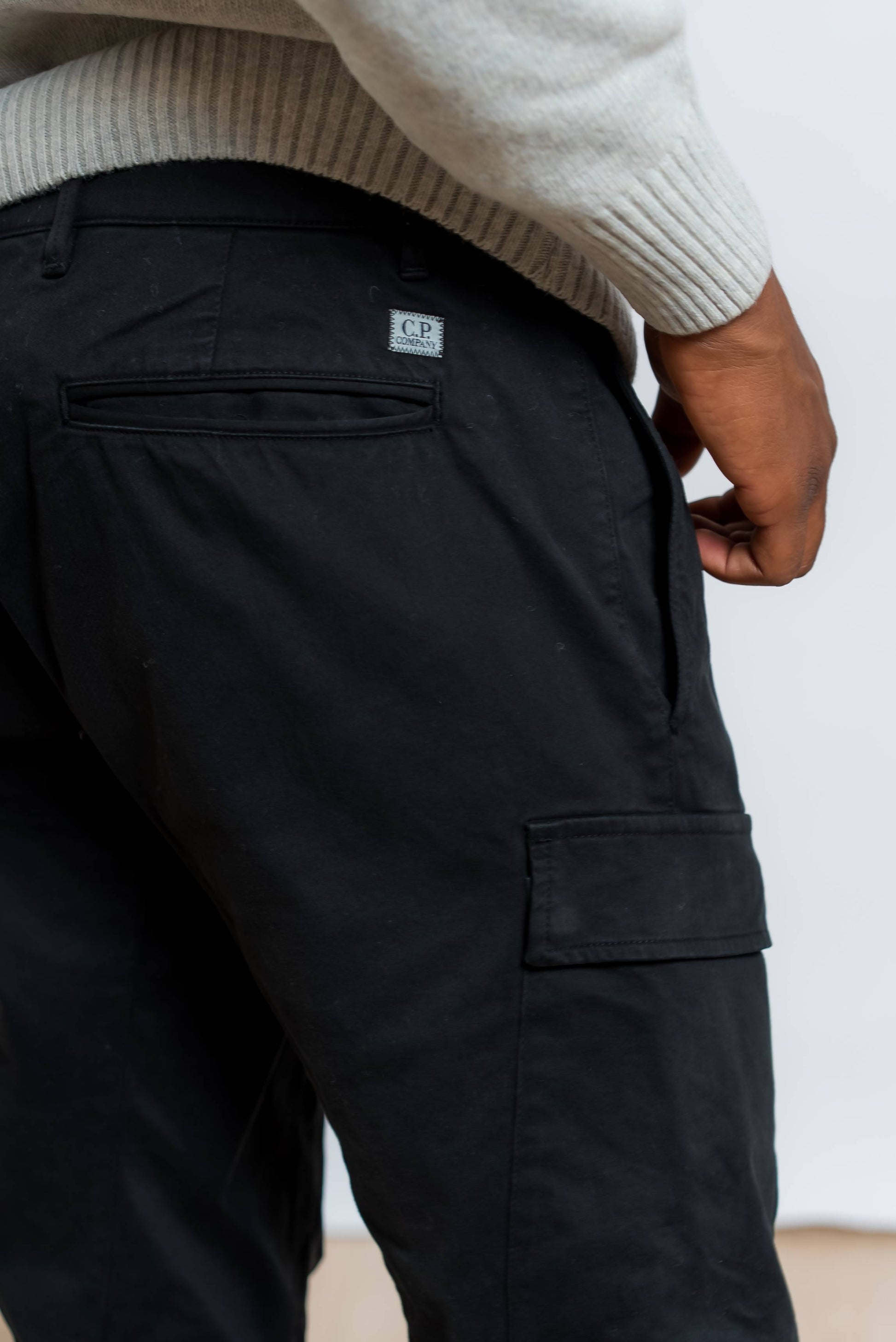 dettaglio tasca ed etichetta con logo cp company sui pantaloni cargo satin stretch neri 