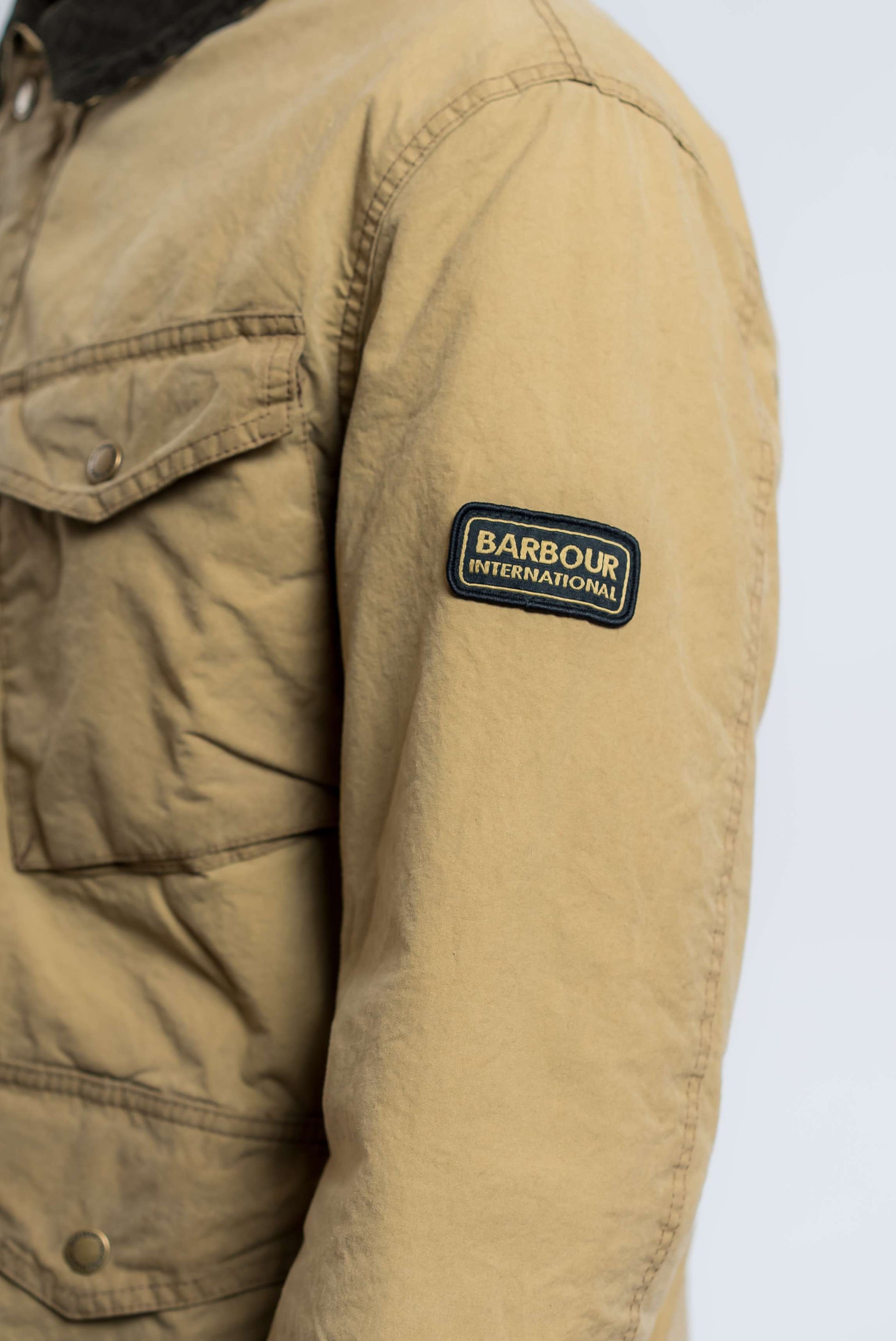 dettaglio etichetta con logo barbour international sul giubbino drifter beige in cotone cerato 