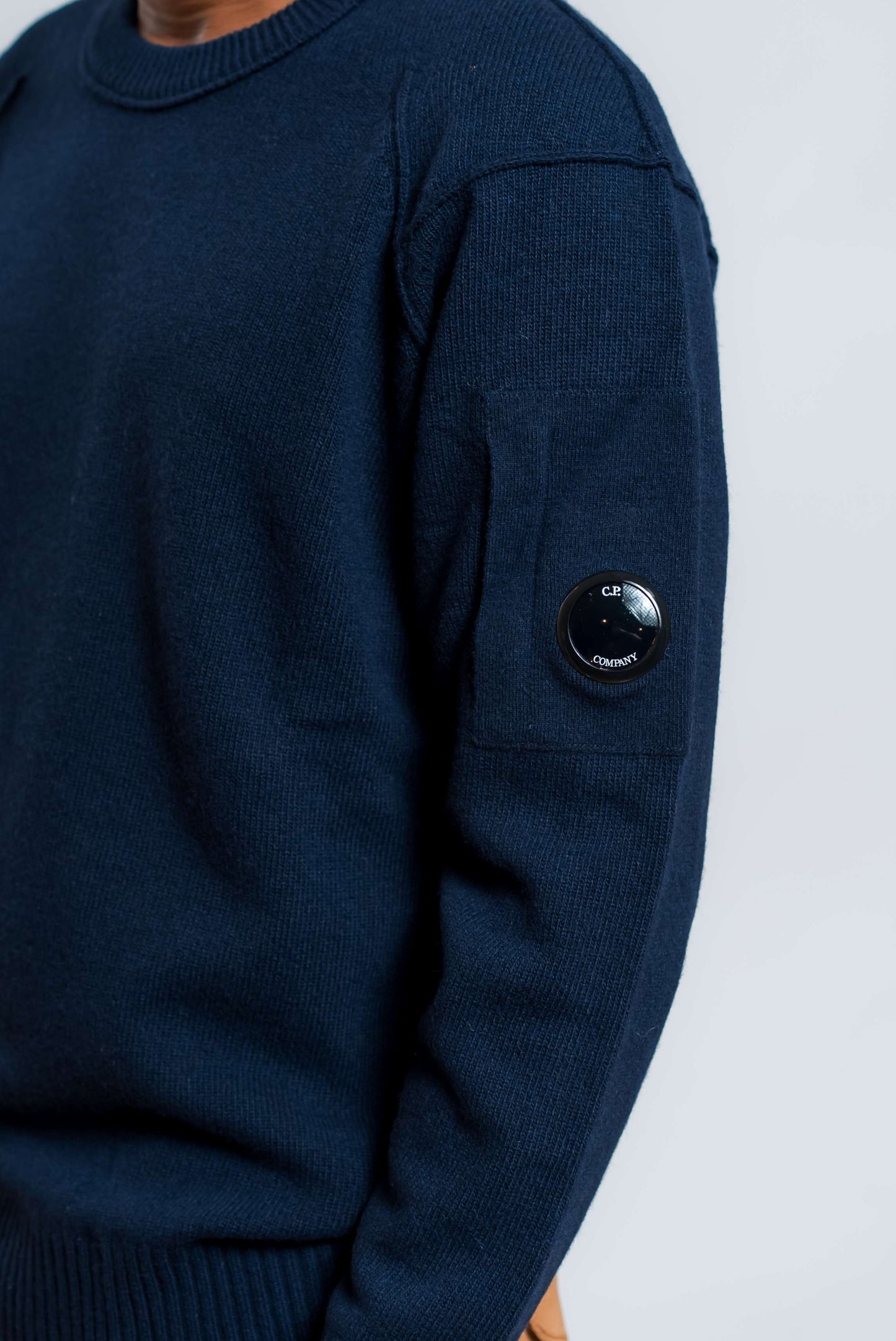 dettaglio del taschino con cp company lens sulla manica del maglione lambswool in lana blu 