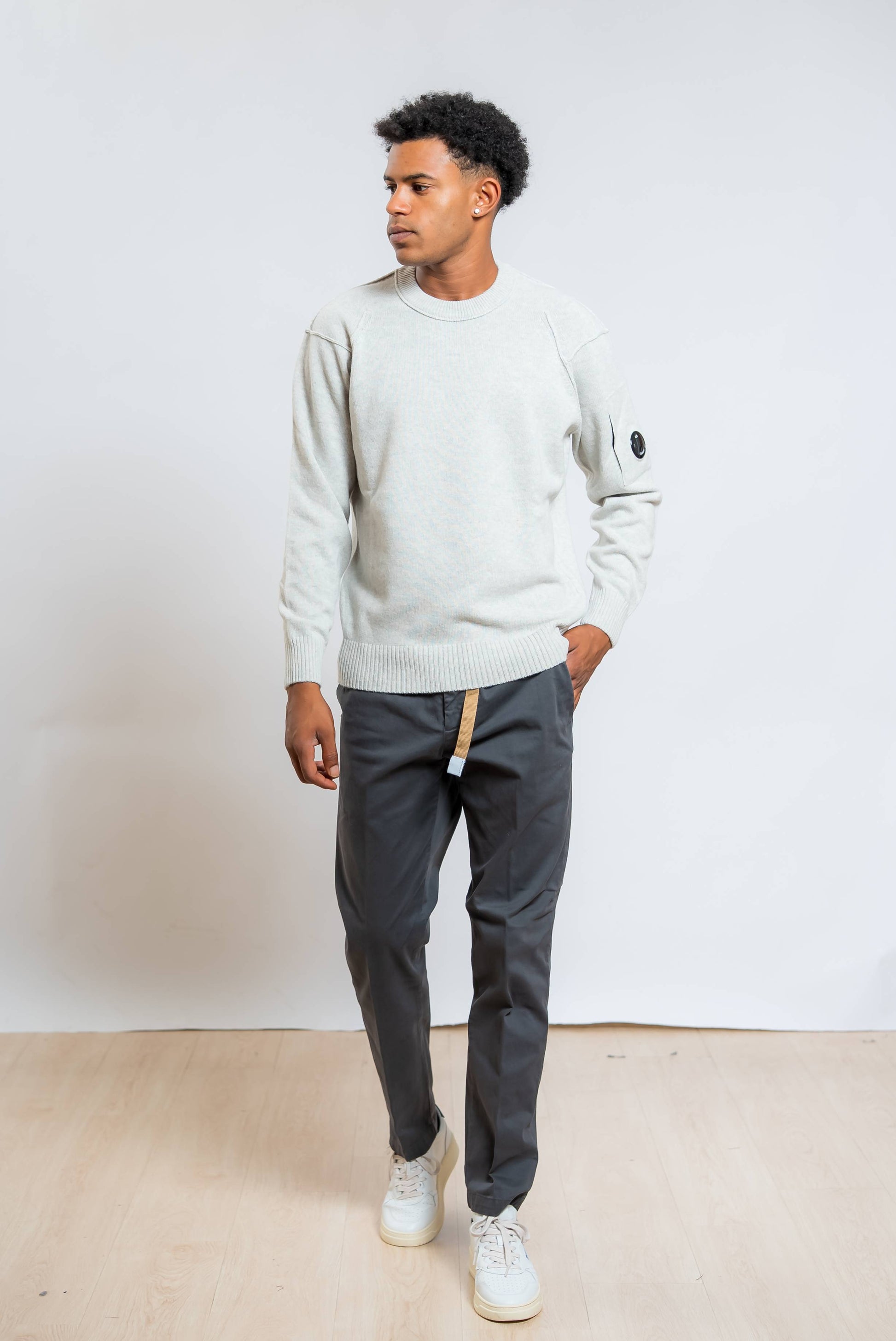 cp company maglione lambswool in lana grigia abbinato ad un pantalone grigio e sneakers bianche