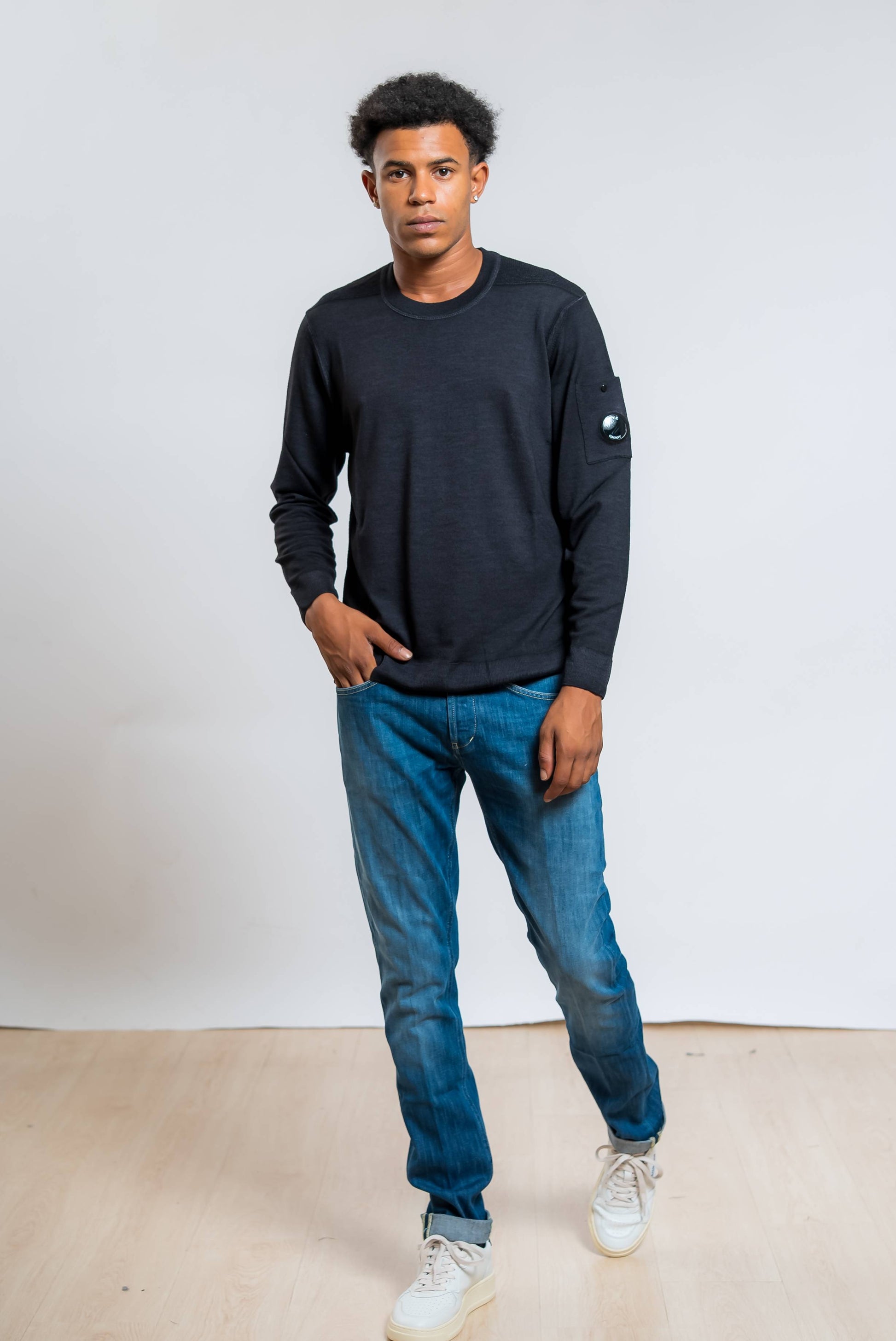 cp company maglia merinos fast dyed in lana nera abbinata ad un jeans blu e sneakers bianche
