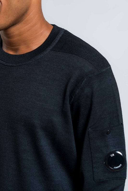 dettaglio della lavorazione sulla spalla e della cp company lens sulla maglia merinos fast dyed in pura lana blu 