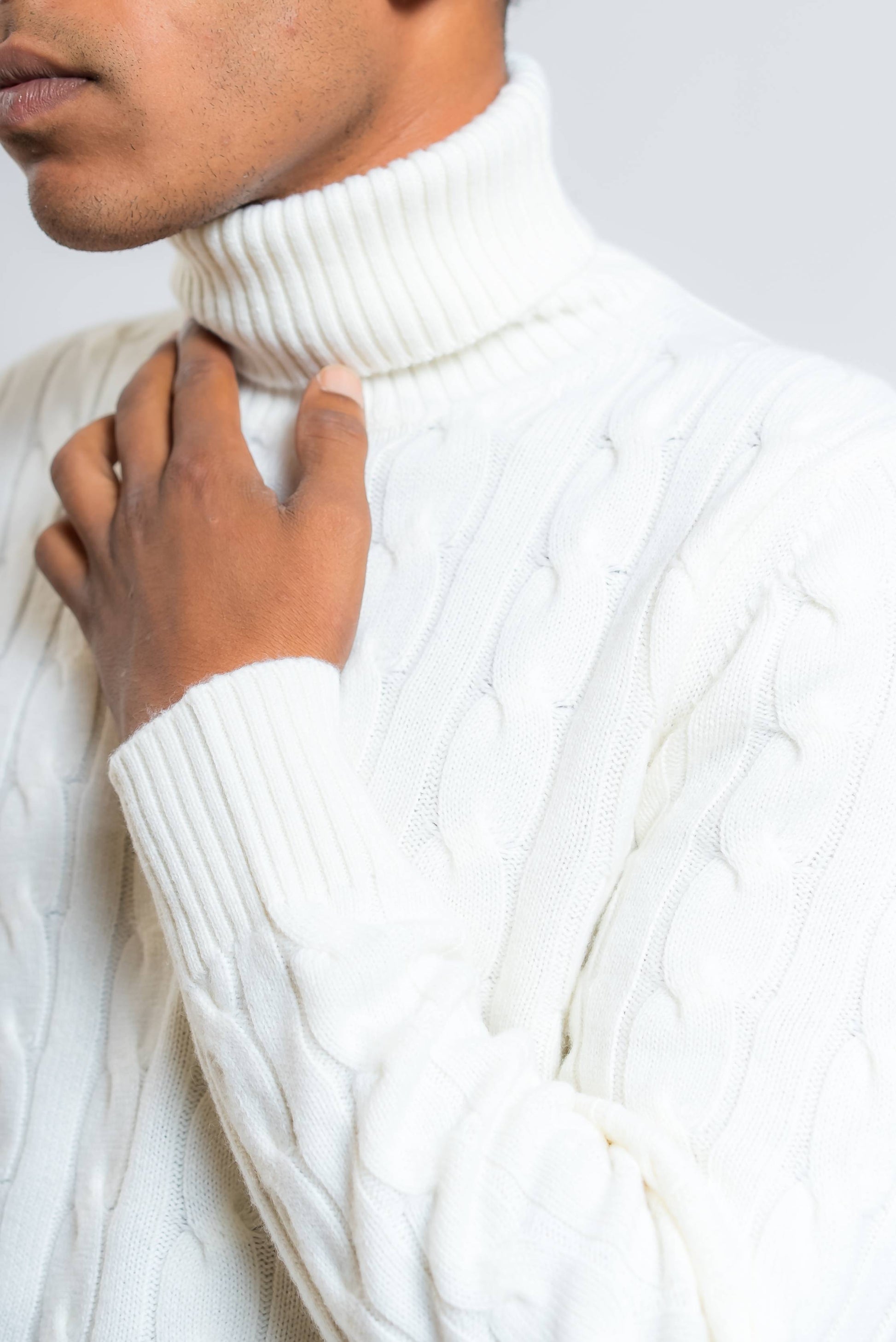 dettaglio del collo alto e polsino lavorato a coste sul maglione a trecce in lana panna di kangra