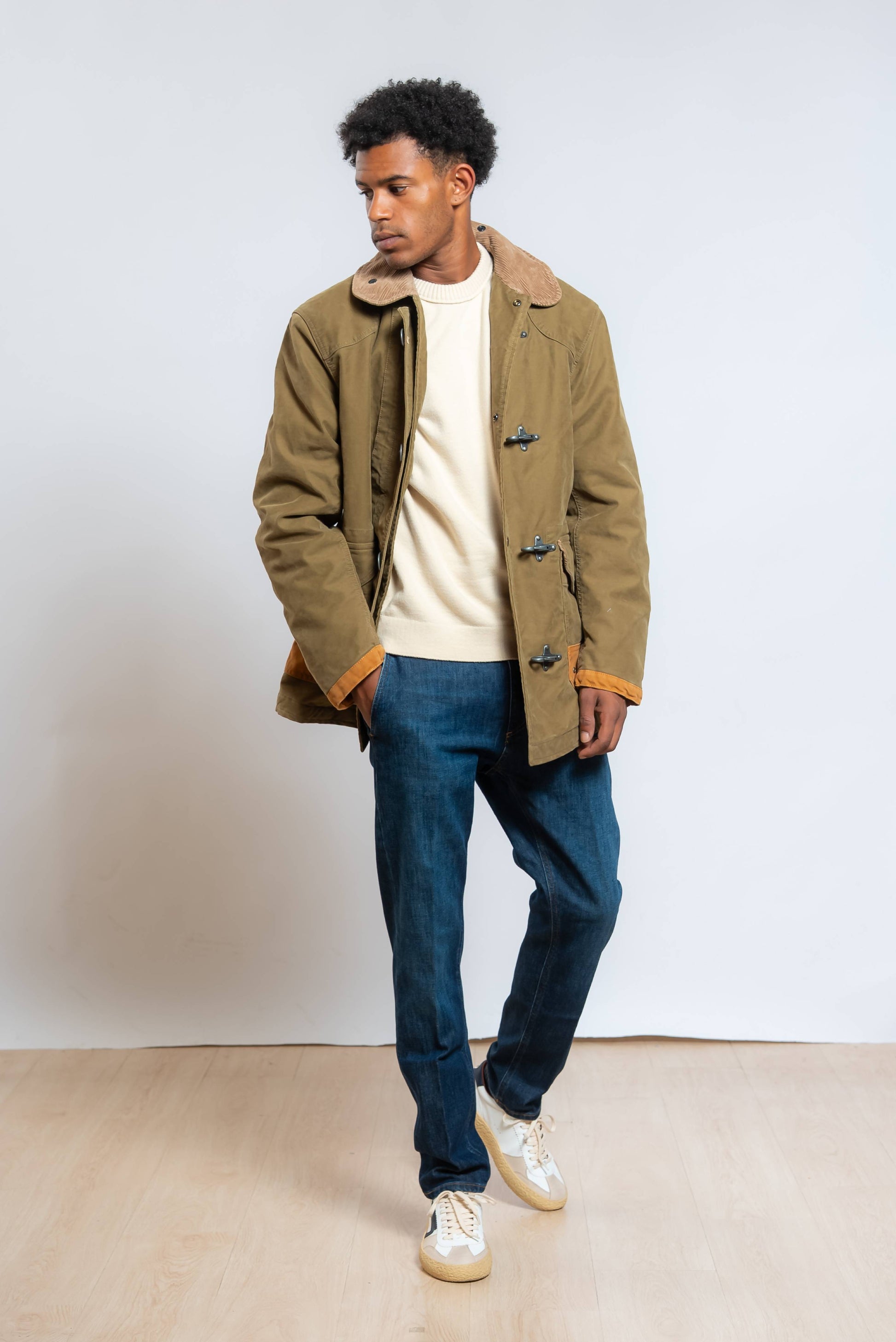 jeans di dondup modello jeff blu con vestibilità carrot fit abbinato ad un maglione beige ed un cappotto verde in cotone 