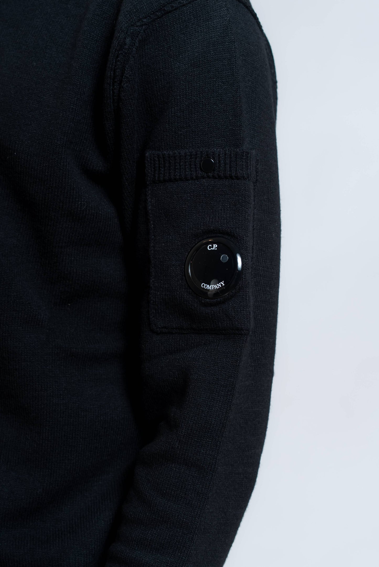 dettaglio cp company lens sul taschino della manica del maglione cotton stretch nero - visuale frontale