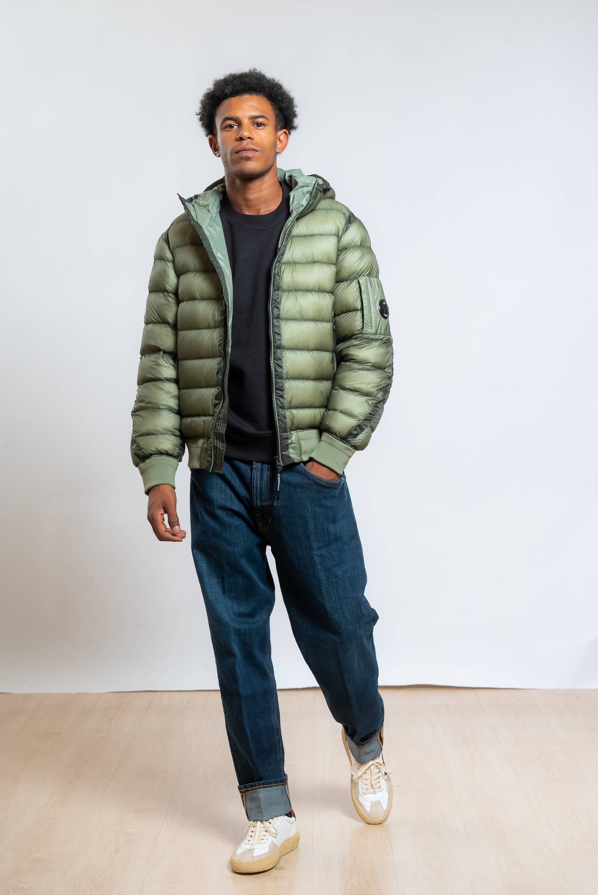 cp company piumino dd shell verde abbinato a jeans loose fit e felpa nera 