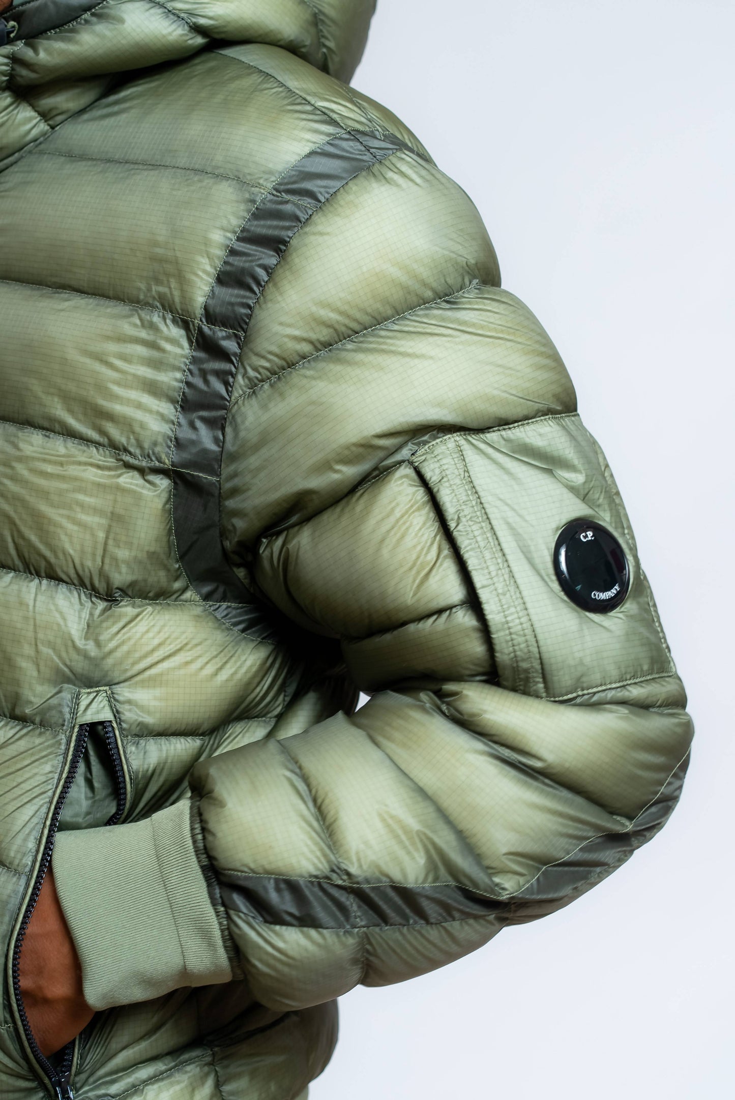 dettaglio della Lens cp company sul piumino dd shell verde imbottito di piuma d'oca