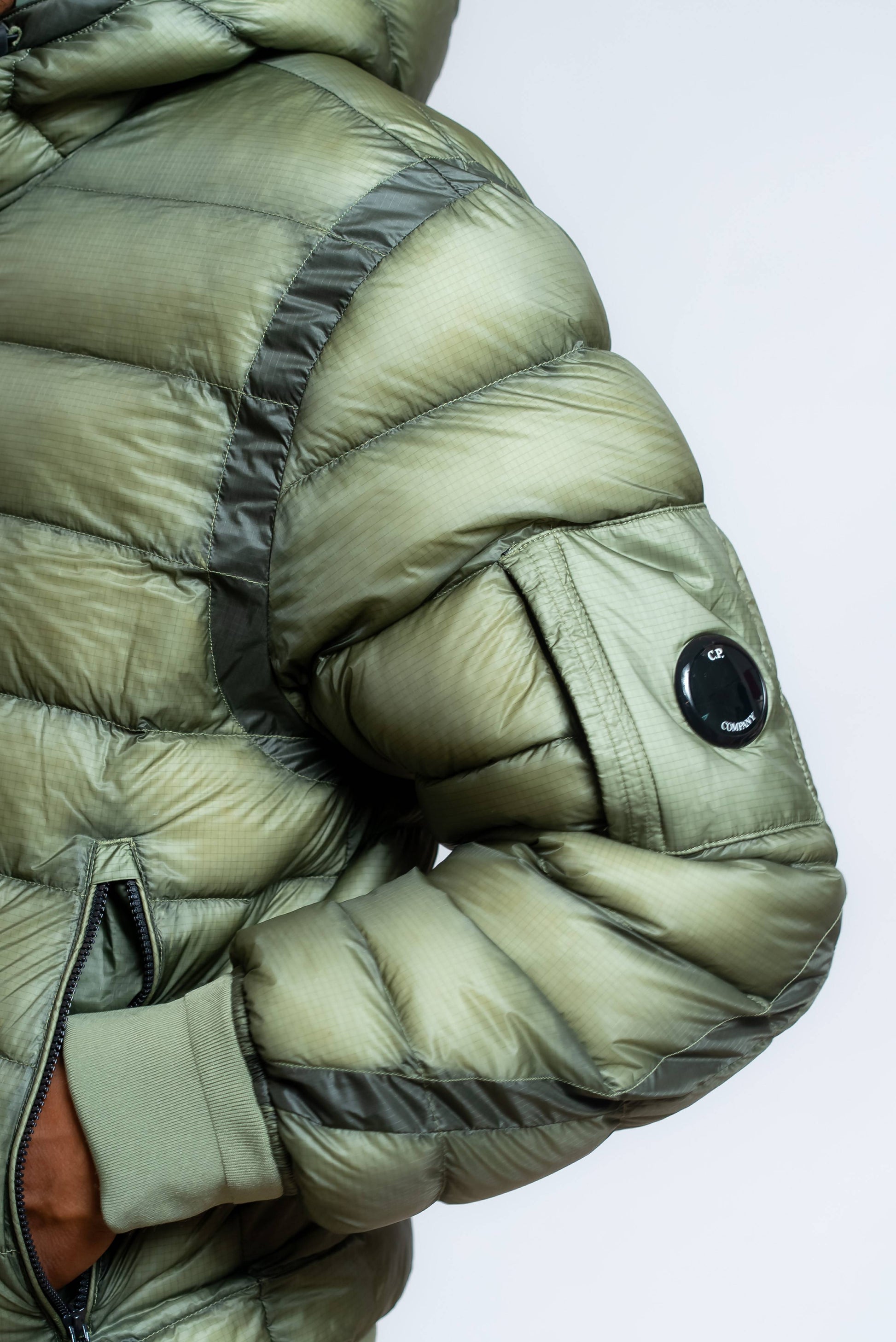 dettaglio della Lens cp company sul piumino dd shell verde imbottito di piuma d'oca