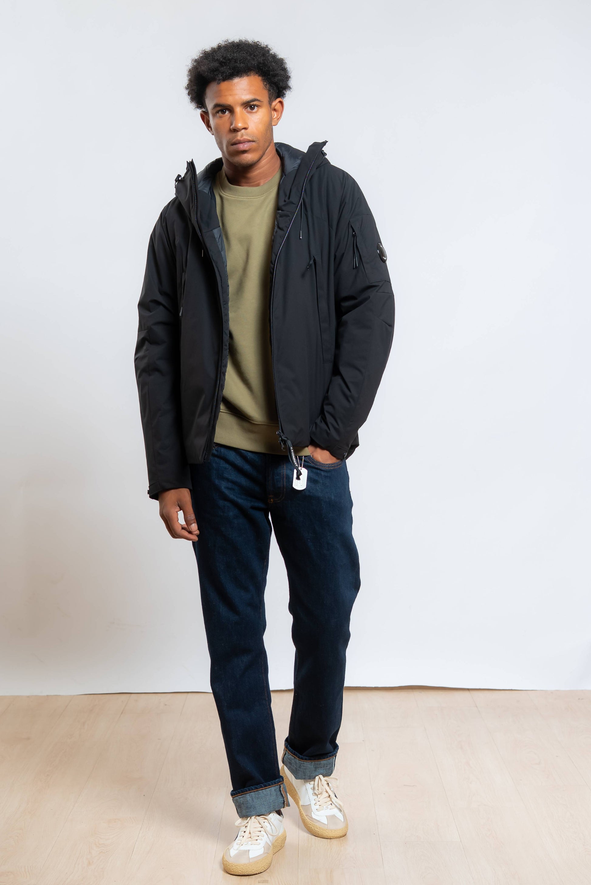  giubbino pro tek medio nero di Cp Company con cappuccio abbinato a felpa verde e jeans