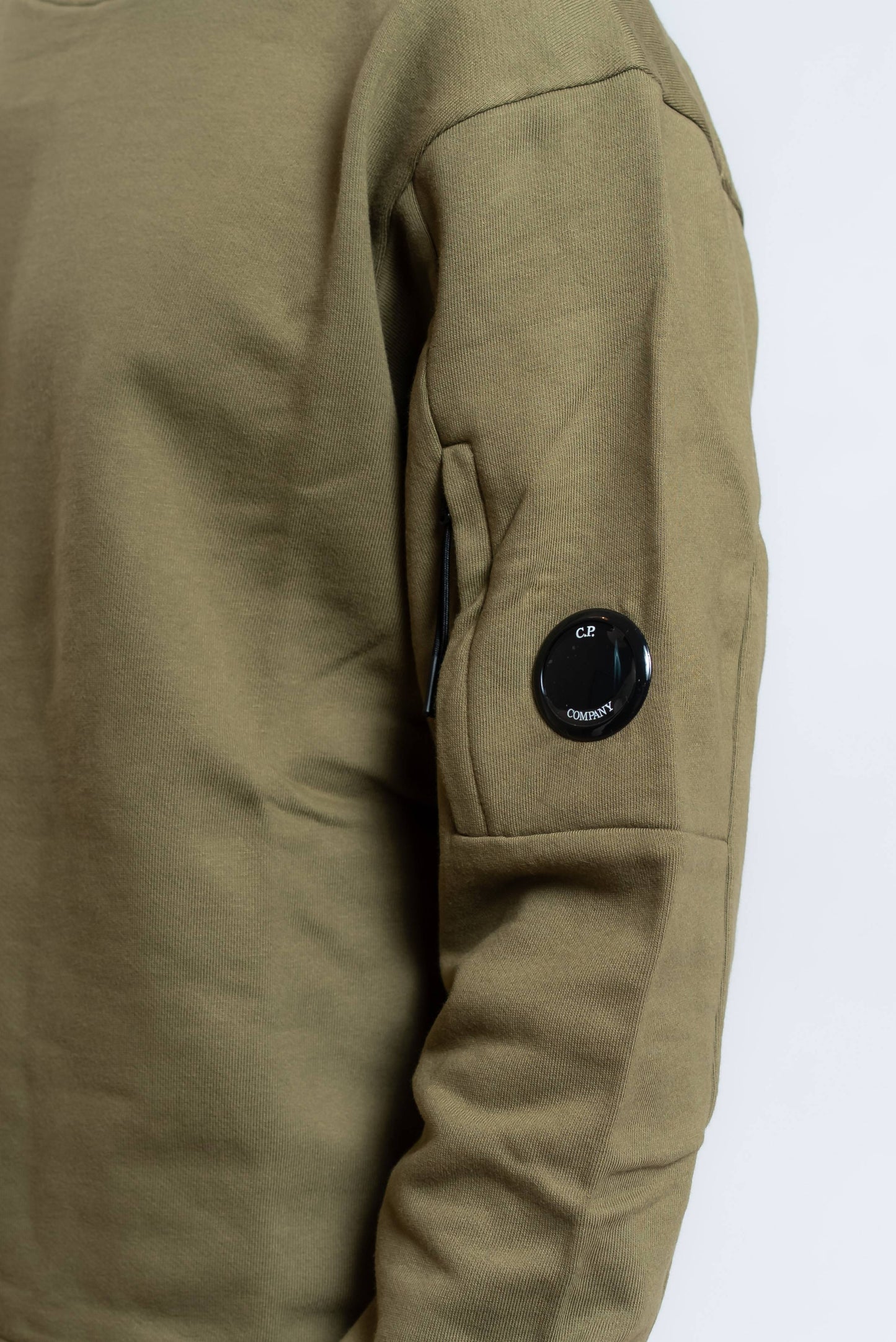dettaglio del taschino con lens cp company sulla manica della felpa a girocollo in cotone verde 