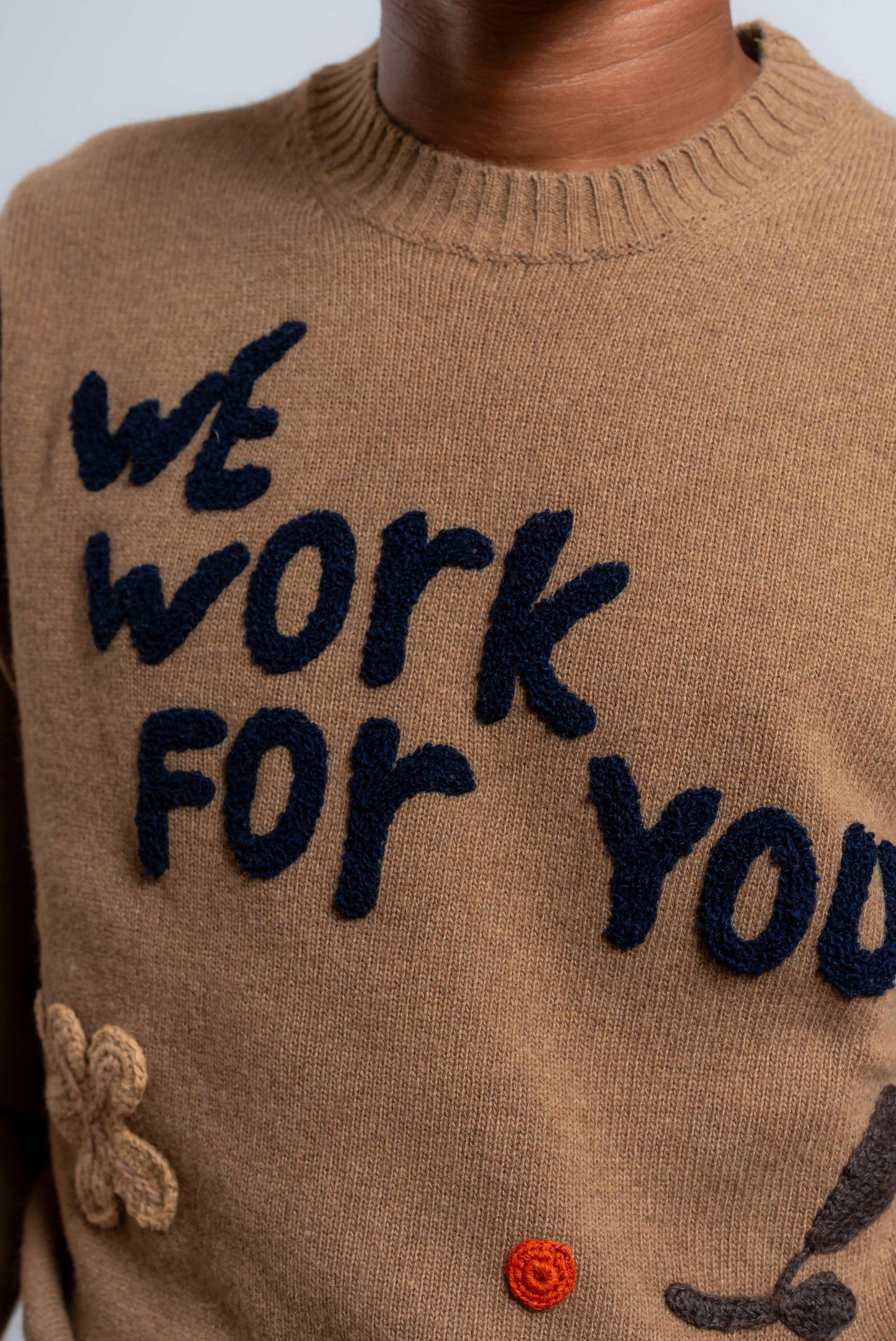 dettaglio dei ricami realizzati a mano sul maglione bond di bob in lana beige scura