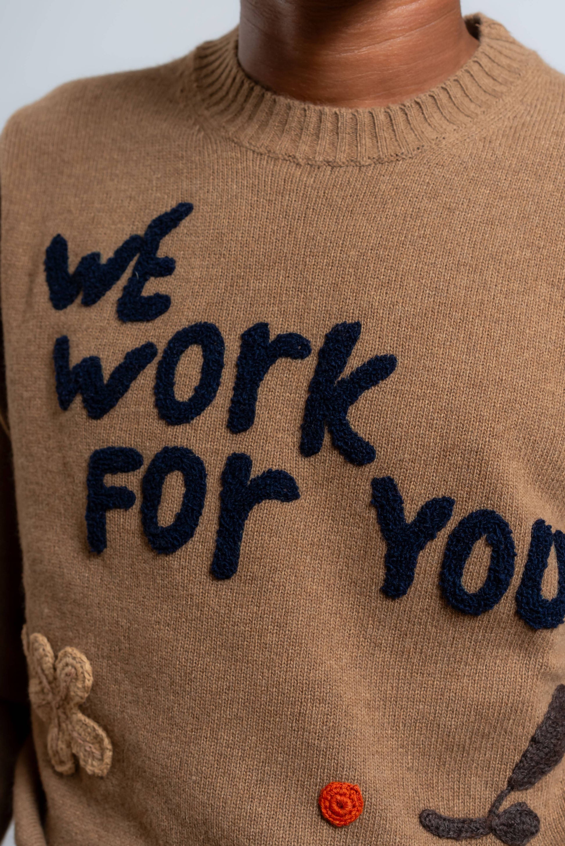 dettaglio dei ricami realizzati a mano sul maglione bond di bob in lana beige scura