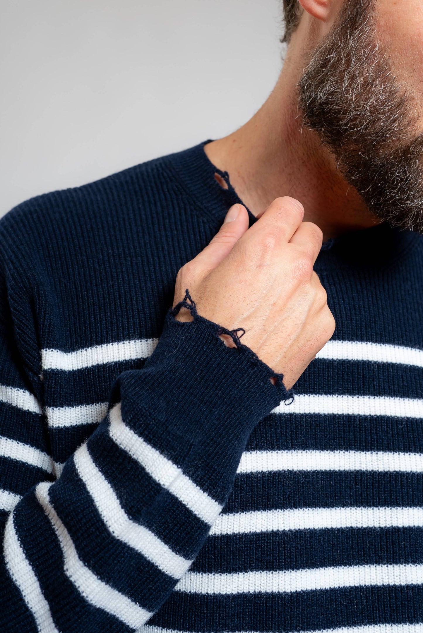 dettaglio delle rotture sugli orli della maglia a righe blu e bianche in pura lana di amaranto