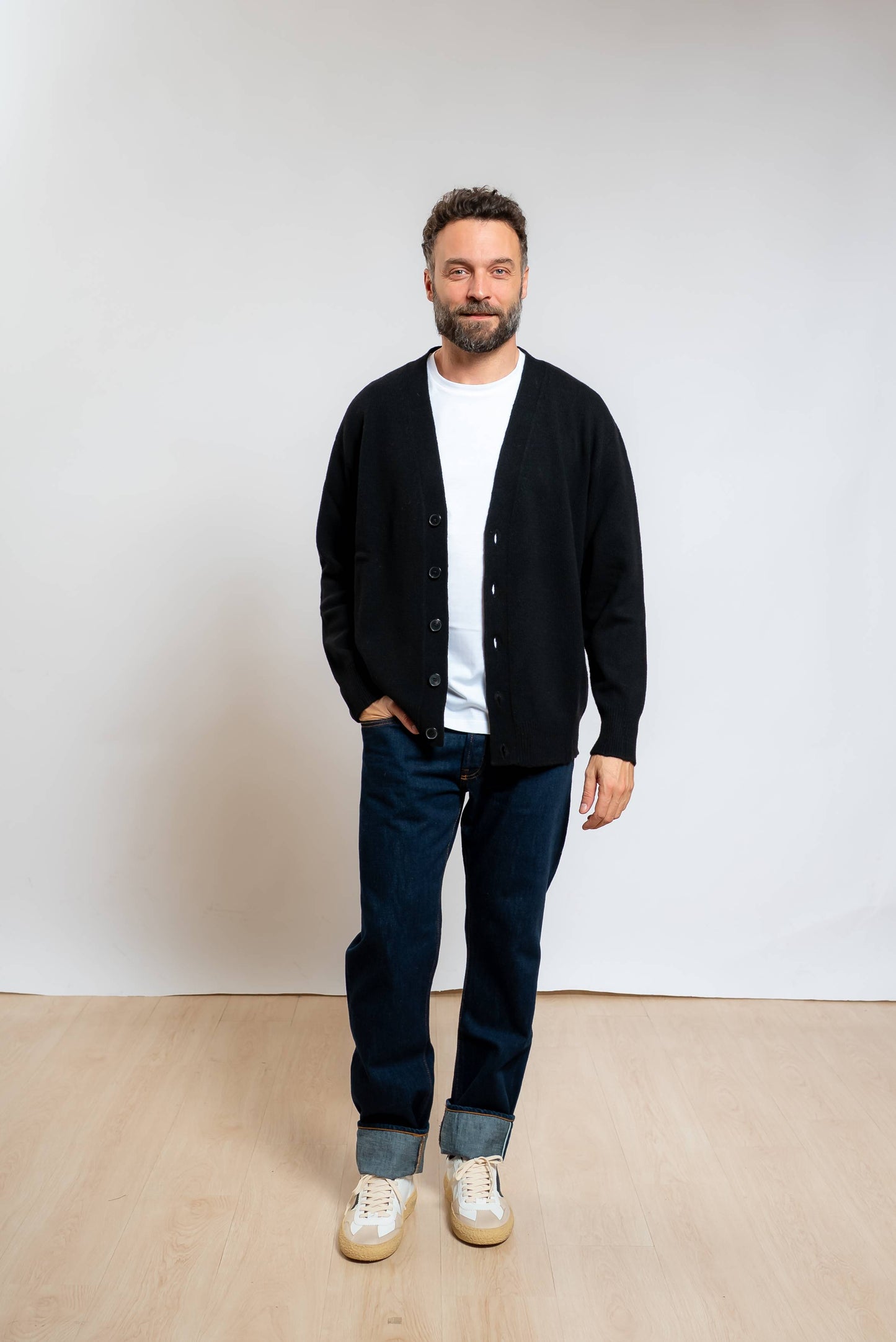 amaranto cardigan in lana e cashmere nero con scollo a v e rotture sugli orli abbinato ad una t-shirt bianca, jeans blu e sneakers bianche