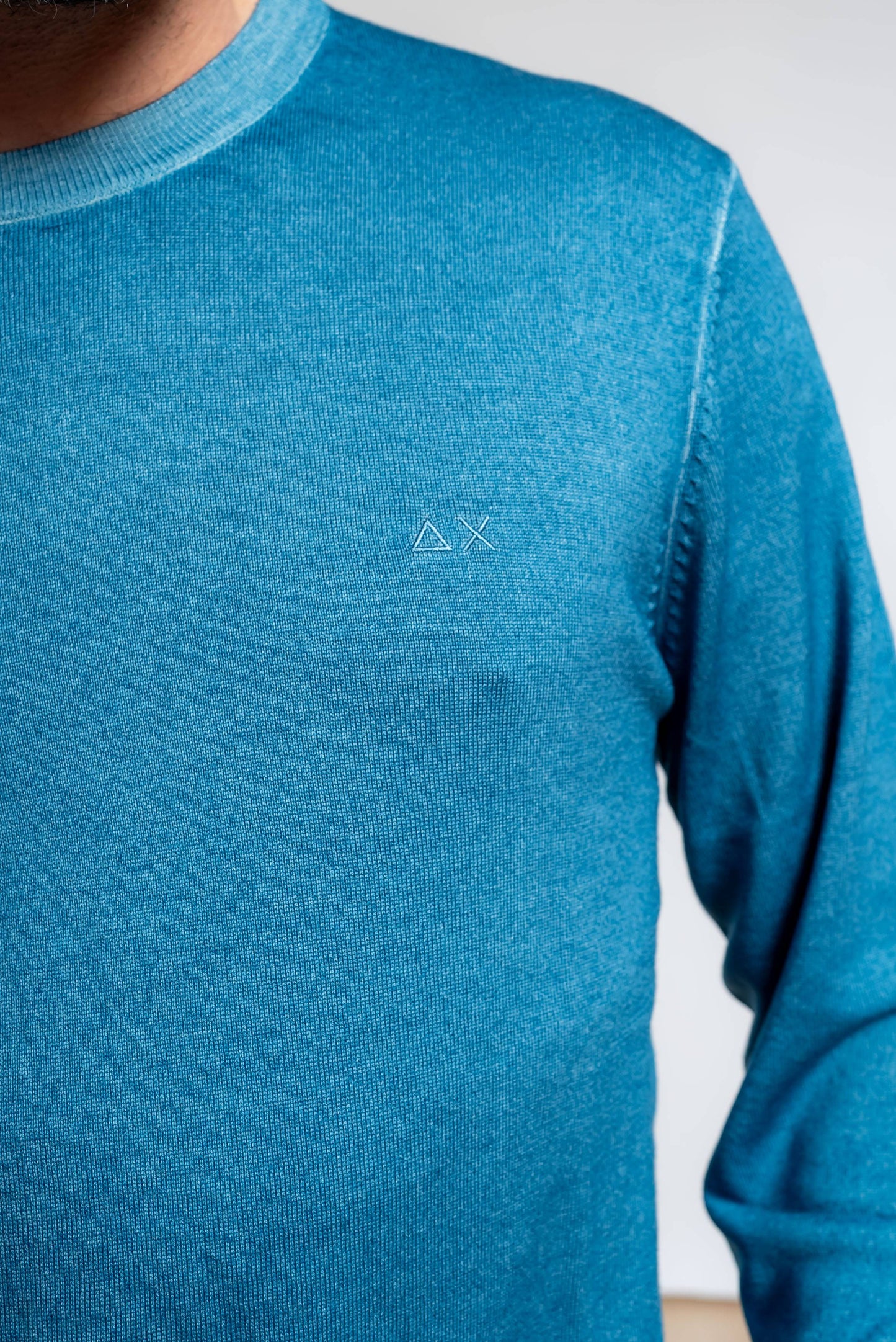 dettaglio del logo sun68 ricamato sulla maglia da uomo azzurra in lana merino con effetto vintage