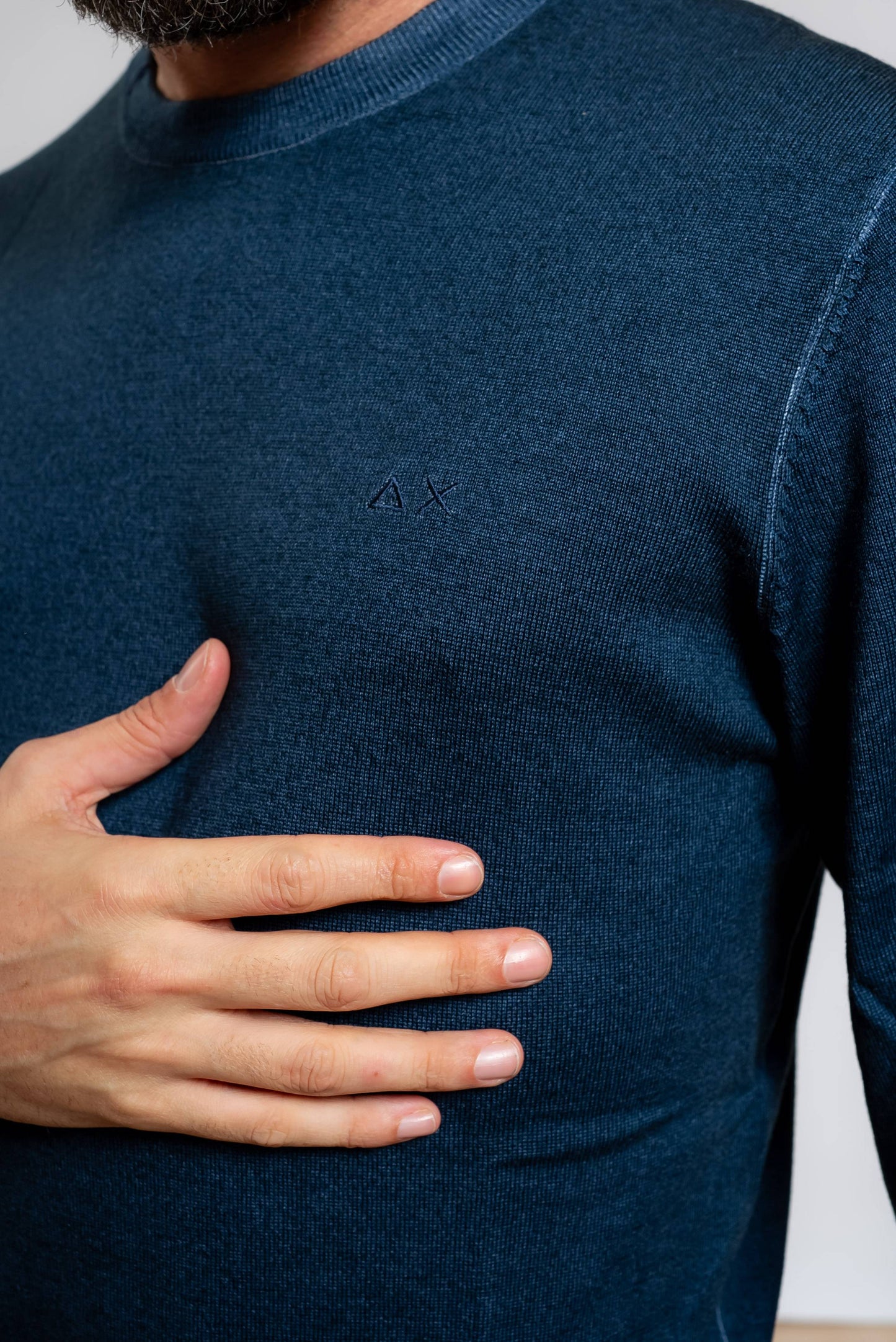 dettaglio del logo sun68 ricamato sulla maglia da uomo a girocollo in lana merino blu con effetto vintage